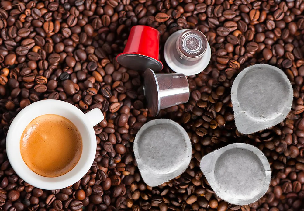 Capsule, cialde, chicchi di caffè e tazzina di espresso